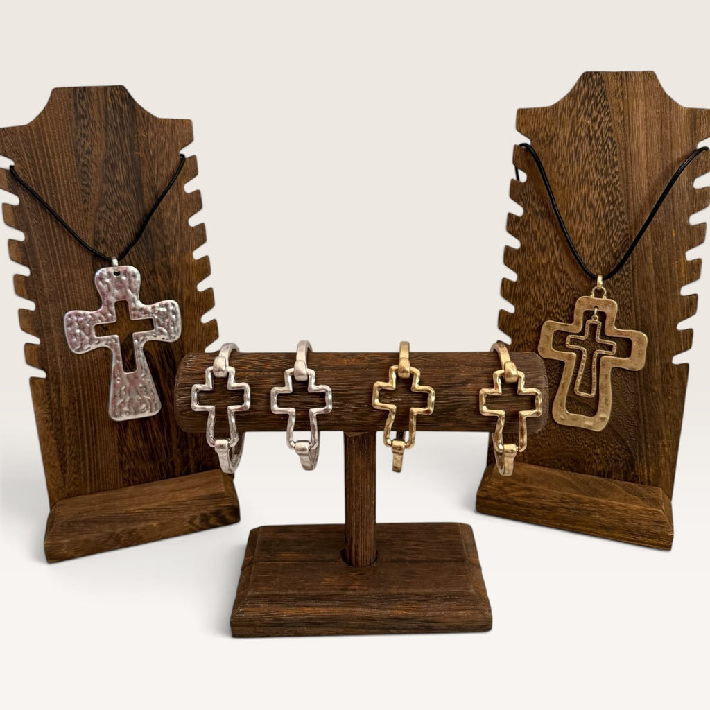 Cross necklace and bracelet sets displayed on rustic wood stands
