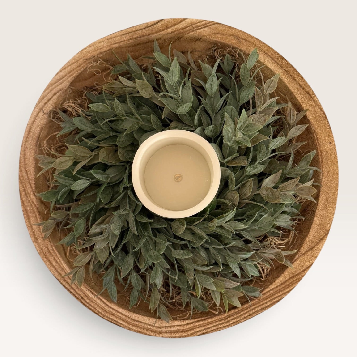 Overhead view of wood bowl centerpiece with faux greenery and LED pillar candle