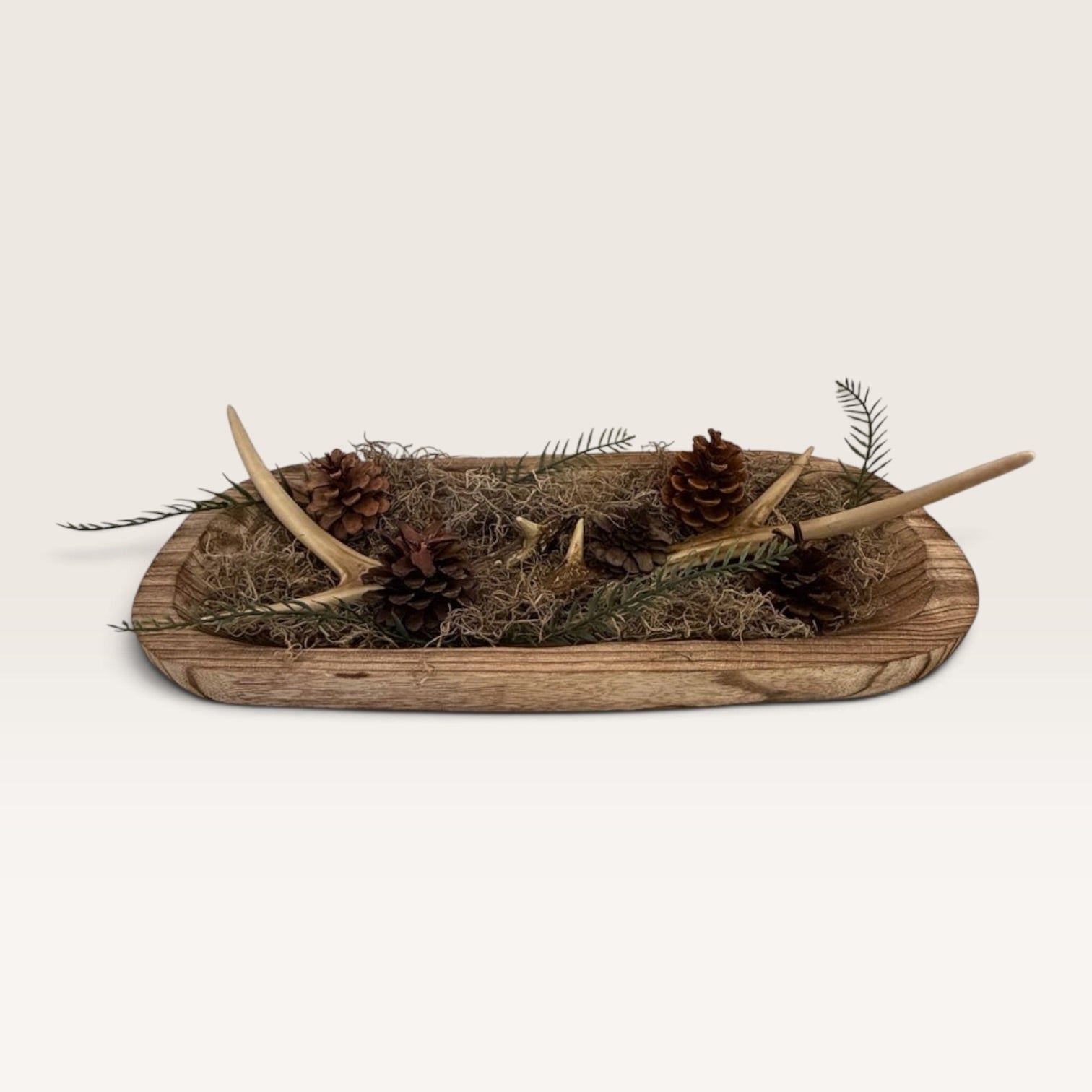 Side angle of handcrafted rustic dough bowl centerpiece with faux antlers and woodland greenery