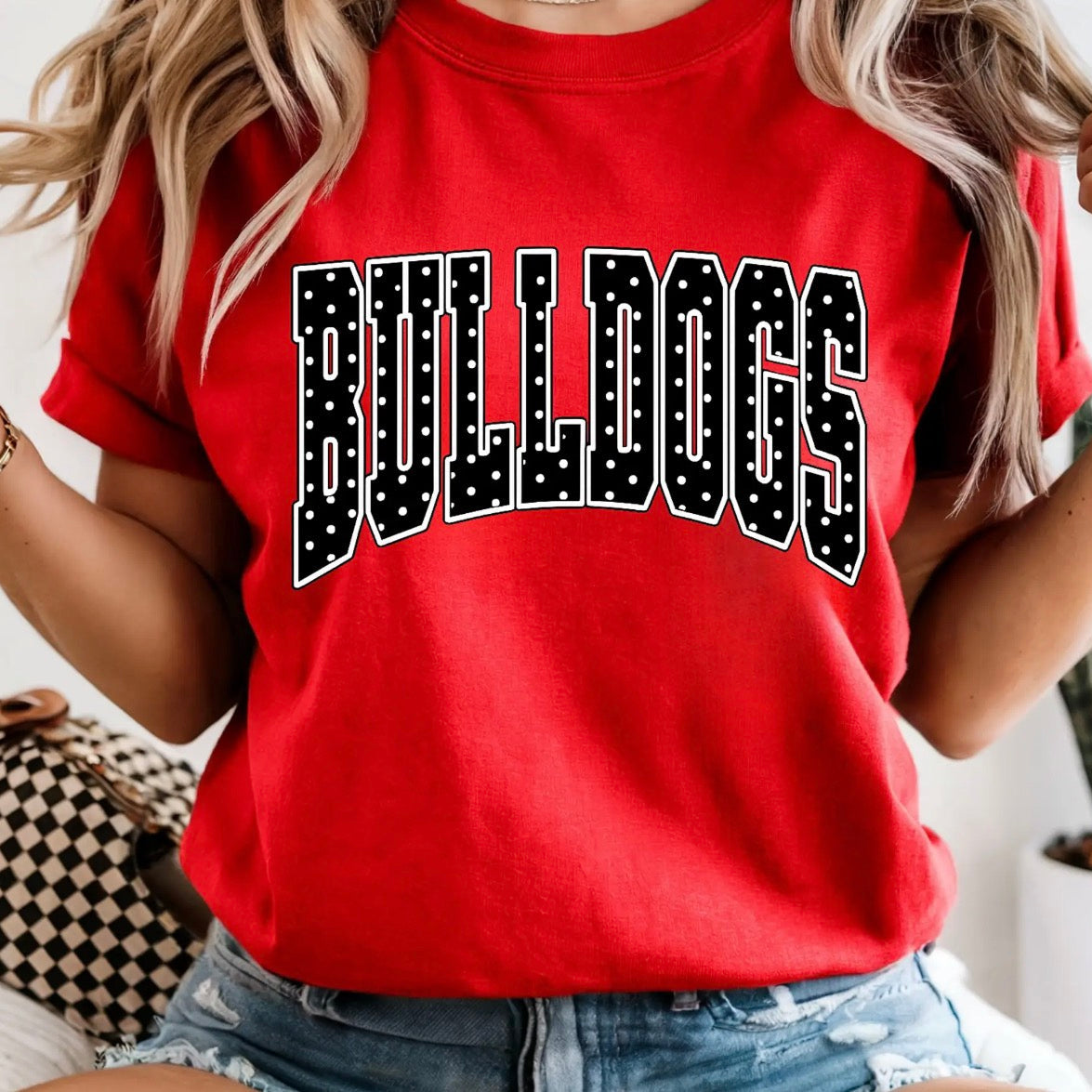 Woman wearing a red Comfort Colors Bulldogs graphic tee with black and white varsity lettering and denim shorts.