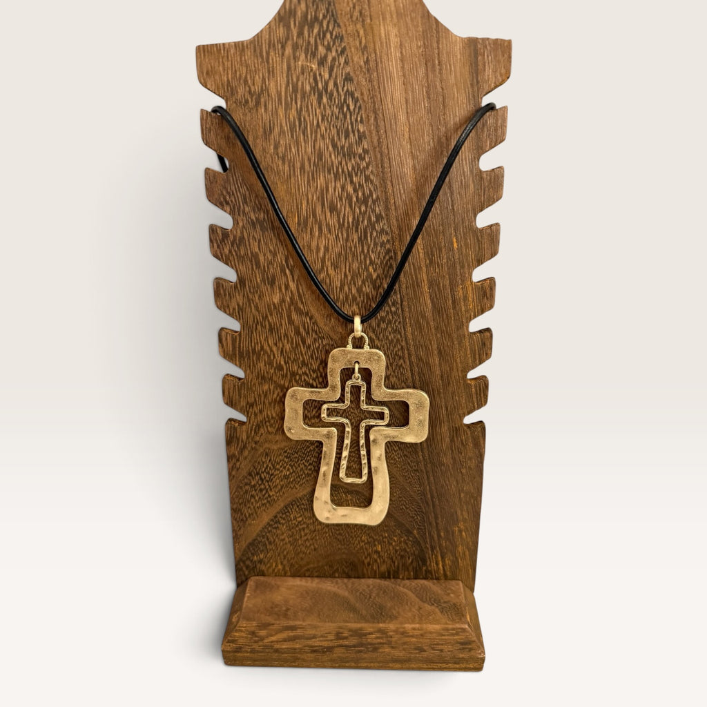 Layered cross necklace displayed on rustic wood jewelry stand