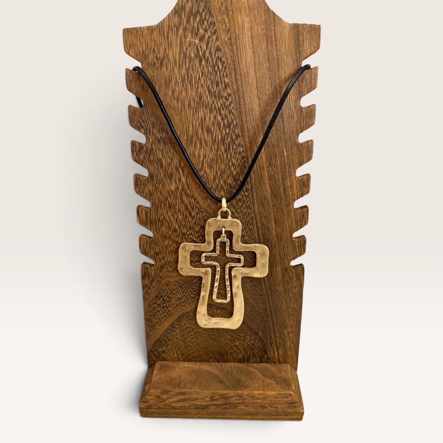 Layered cross necklace displayed on rustic wood jewelry stand