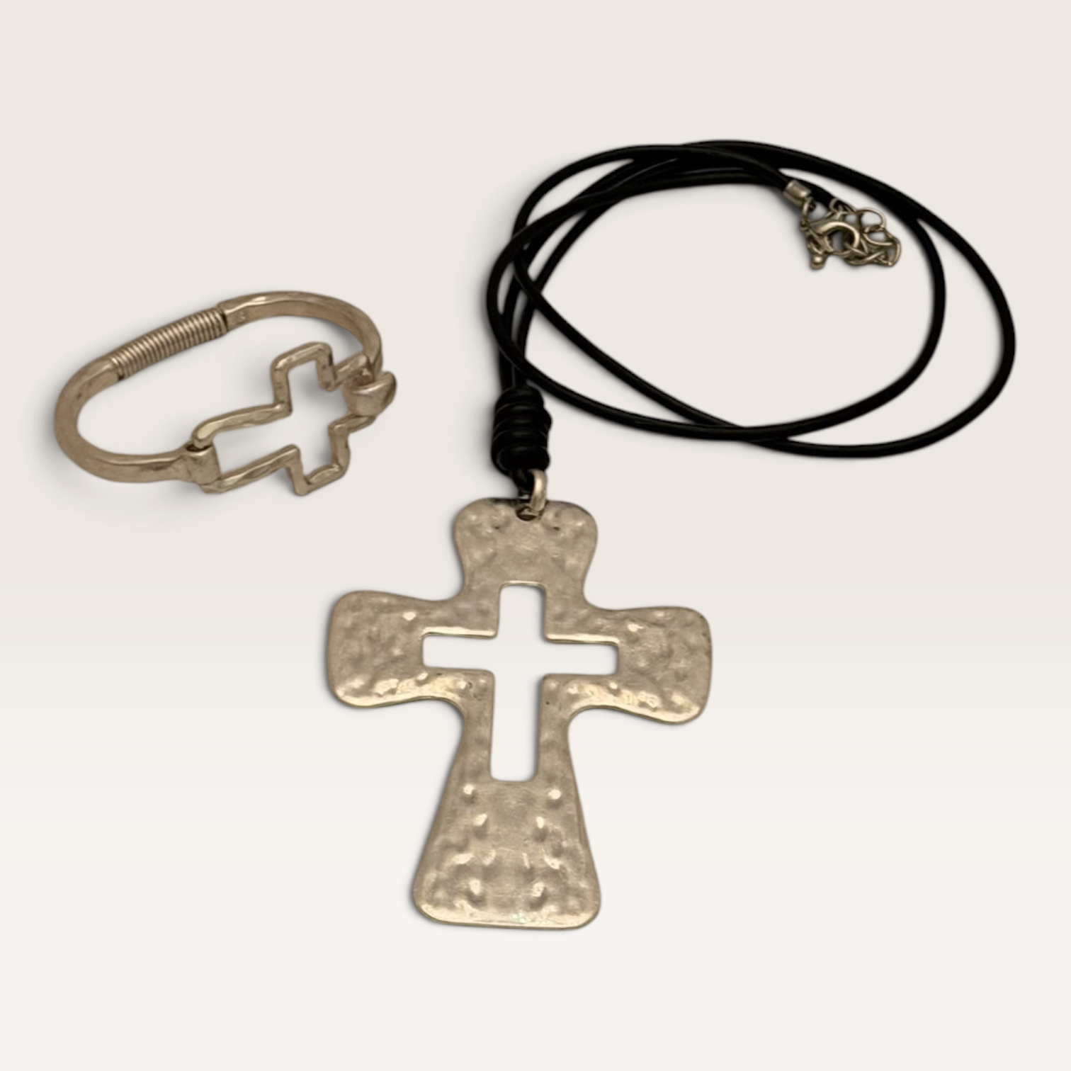 Red Clay Mercantile silver hammered cross pendant necklace on a black cord and matching open-frame cross bracelet.